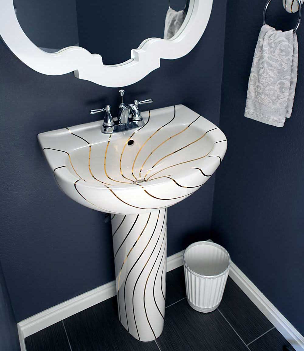 custom navy powder room with cool pedestal lavatory painted with gold swirling lines and decorative white mirror.