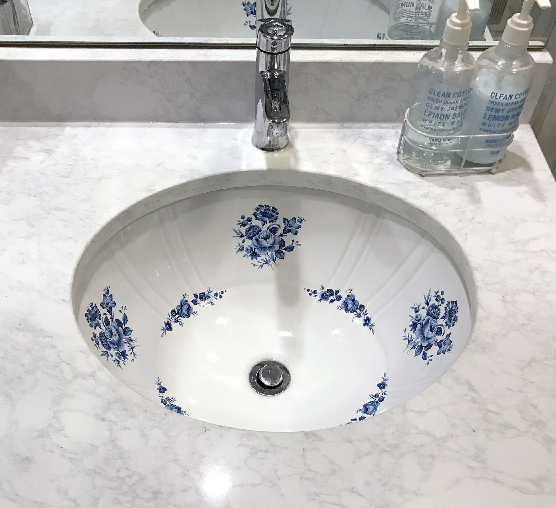 Fluted undermount bathroom sink painted with blue roses in white marble counter